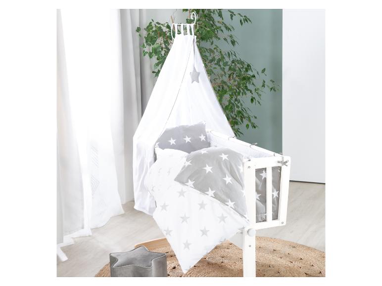 Babybett mit Himmel und Sternenmuster-Bettwäsche in einem Kinderzimmer.