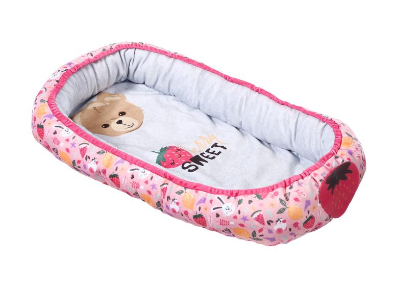 Rosa Babynest mit Erdbeer-, Zitronen- und Hasenmustern, mit einem Bären innen.