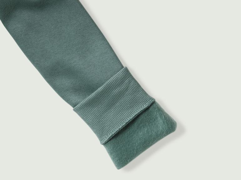 Ein grüner, weicher Pullover mit geripptem Bündchen.