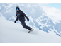 Snowboarder in dunkelblauem Snowboardanzug fährt einen verschneiten Berghang hinunter.