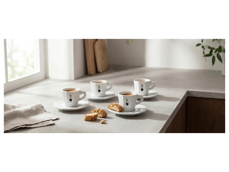 Vier Espressotassen mit Keksen auf einer hellen Küchenarbeitsplatte.