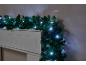 Weihnachtsgirlande mit weißen LED-Lichtern über einem weißen Kaminsims.
