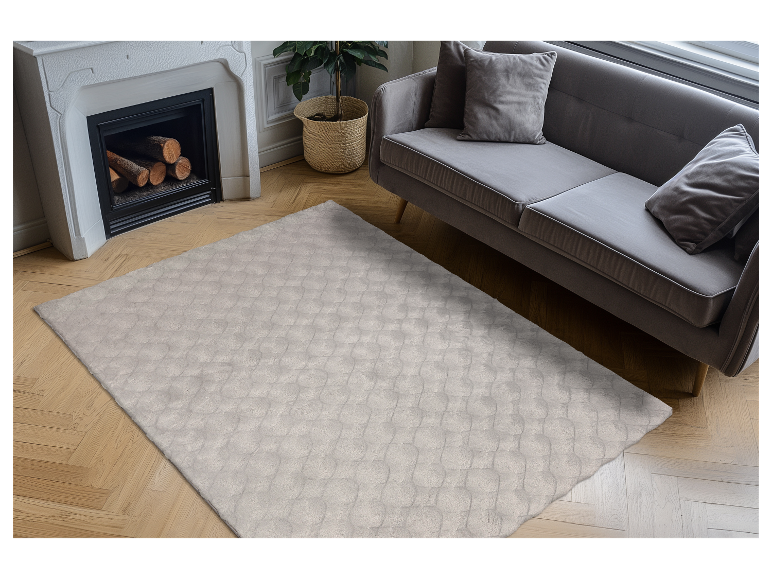 Hellgrauer Teppich mit geometrischem Muster vor einer grauen Couch.