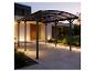 Moderner Carport mit transparentem Dach und Beleuchtung am Hauseingang.