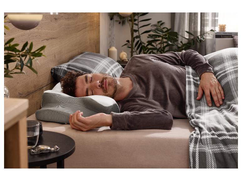 Mann schläft tief und fest auf einem konturierten Memory-Schaum-Kissen in einem gemütlichen Schlafzimmer.