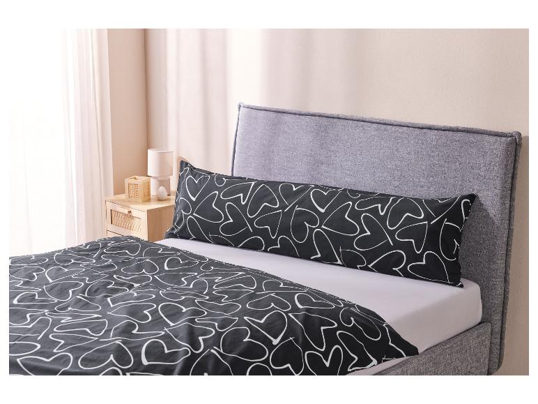 Ein Bett mit schwarzer Bettwäsche und Kissen mit weißem Herzmuster.