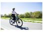 Frau auf einem E-Bike auf einem sonnigen Radweg.