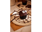 Halloween-Spinnen-Cupcake mit Schokostreuseln und Zuckeraugen auf einem Teller.