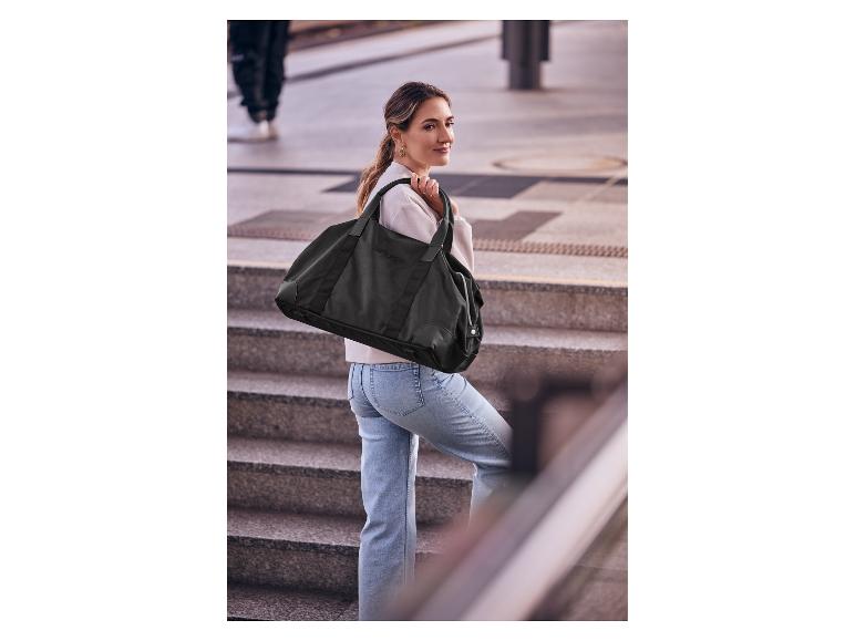 Eine Frau auf einer Treppe mit einer ESMARA® Weekender-Tasche.