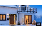 Haus mit Weihnachtsbeleuchtung, Weihnachtsbäumen und Lichtdekorationen in einer Schneelandschaft.