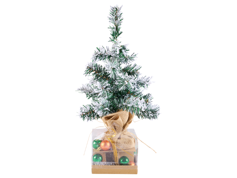 Kleiner verschneiter Weihnachtsbaum in einer dekorativen Schachtel mit Kugeln.