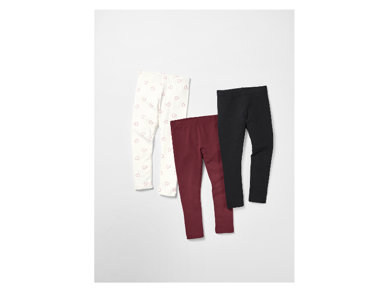 Drei Leggings für Mädchen: eine mit Herzmuster, eine burgunderrot und eine schwarze.