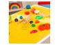 Bunte Knete und Spielwerkzeuge auf einer gelben Matte mit Essensmotiven.