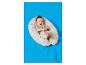 Ein lächelndes Baby in einem beigen Body auf einem gepunkteten Stillkissen auf einer blauen Decke.