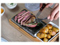 Ein Steak, das auf einem heißen Stein mit gebackenen Kartoffeln serviert wird.