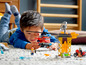 Ein Kind spielt mit einem LEGO City Feuerwehrhelikopter und einer Feuerwehrstation.