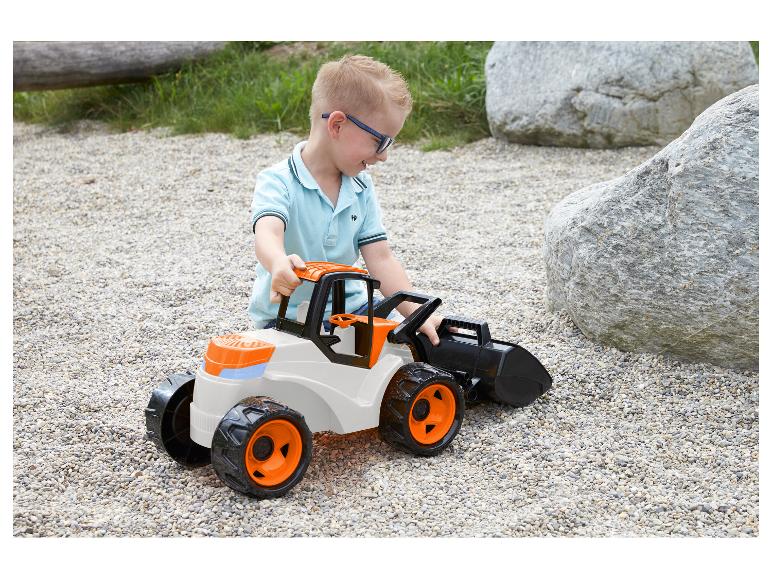Kind spielt mit dem LENA GIGA TRUCKS Schaufellader auf feinem Kies.
