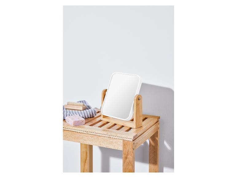 Ein weißer Spiegel auf einem Holzregal mit Seife und einer Bürste.