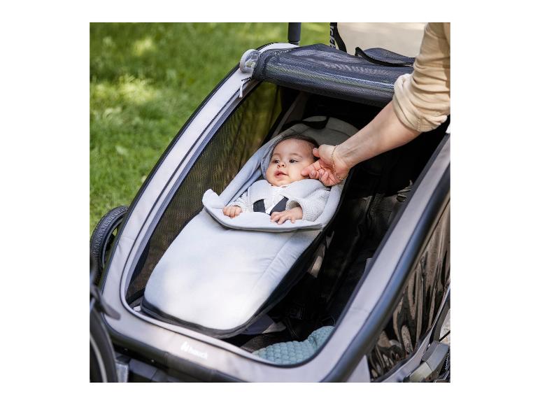 Baby in grauer Babyschale in einem Hauck Fahrradanhänger