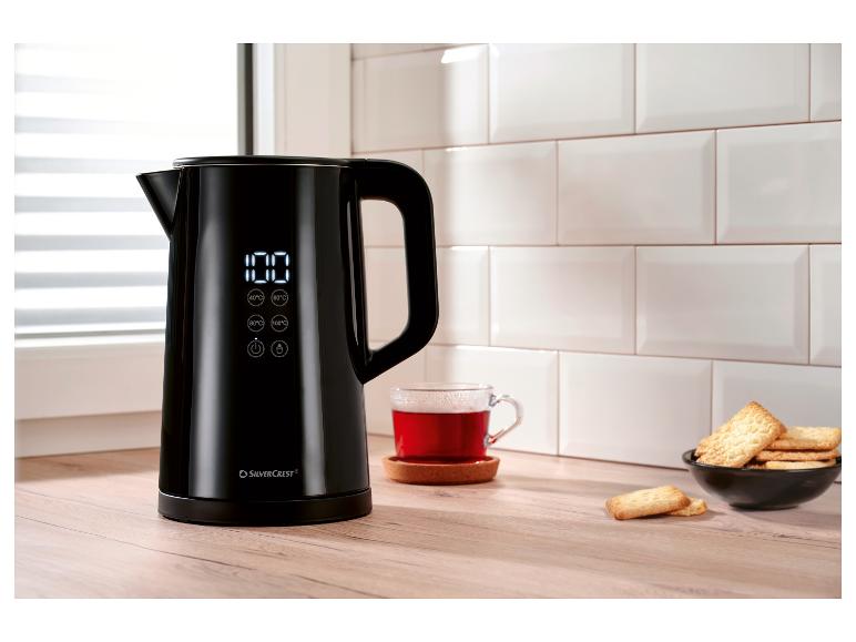 Schwarzer SilverCrest Wasserkocher mit Digitalanzeige, Tasse Tee und Kekse in der Küche.