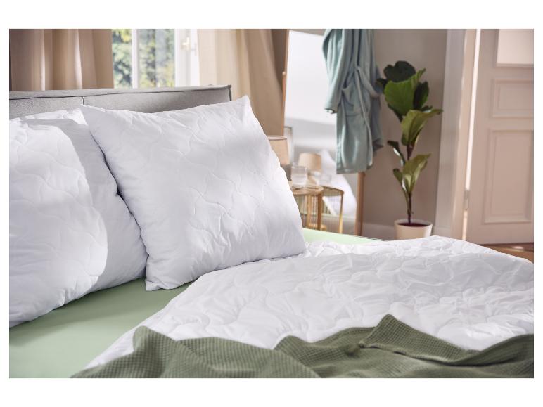 Weiße Kissen und Bettdecke mit grünem Laken und Decke im Schlafzimmer.