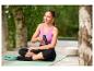Eine Frau benutzt eine CRIVIT Mini-Massage-Gun auf einer Yogamatte.
