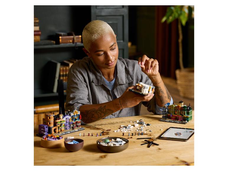 Eine Frau baut ein LEGO-Set zusammen, mit anderen LEGO-Modellen auf dem Tisch.