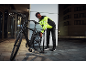 Mann in reflektierender Jacke pumpt nachts einen Fahrradreifen auf.
