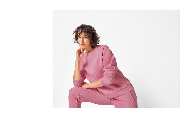 Eine Frau trägt einen rosa Hoodie und eine Hose.