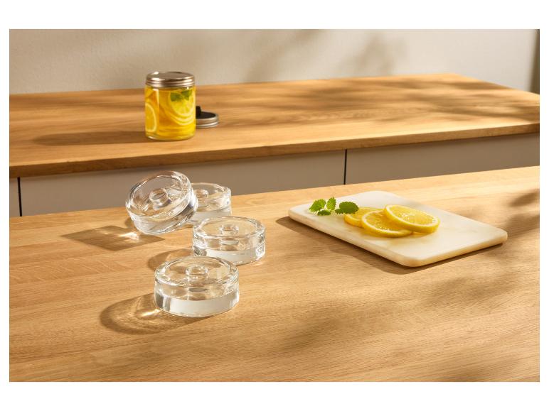 Teelichthalter aus Glas auf einer Holzarbeitsplatte mit Zitronen und Minze.