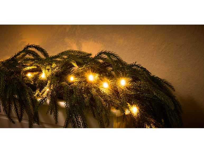 Weihnachtsgirlande mit warmweißer LED-Beleuchtung vor hellem Hintergrund.