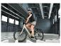 Frau mit Helm und Sonnenbrille fährt E-Bike in einer Halle.