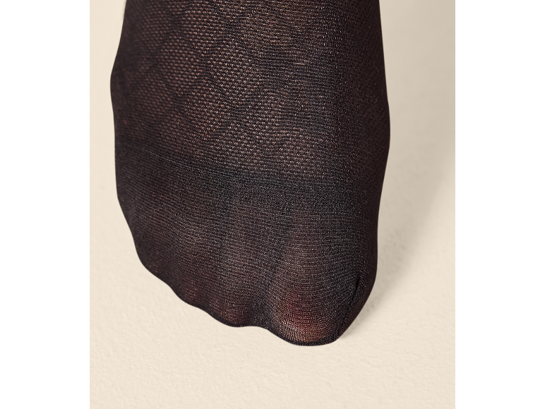 Schwarze Strumpfhose mit transparentem Stoff, der den Fuß bedeckt.