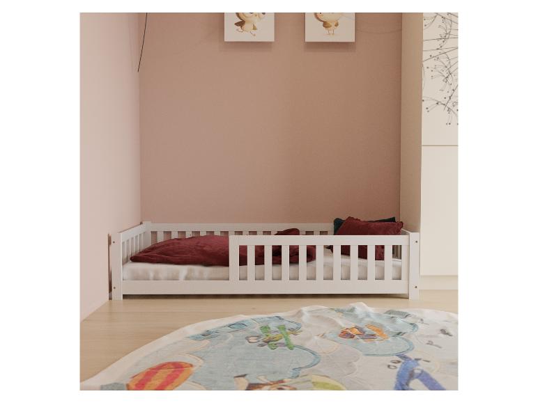 Weißes Kinderbett mit roter Bettwäsche und Kissen in einem rosa Zimmer.