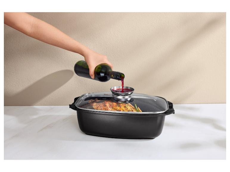 Hand gießt Rotwein in einen Bräter mit Glasdeckel, der gekochtes Essen enthält.