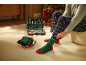 Ein Mann in karierter Pyjamahose zieht sich neben einem Werkzeugkoffer grüne Weihnachtssocken an.