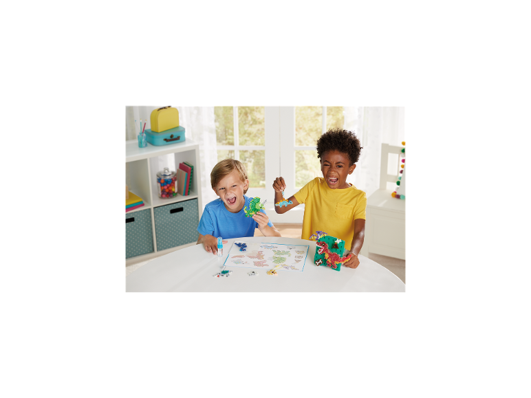 Zwei Jungen lachen und halten dinosaurierförmige Bastelperlen.