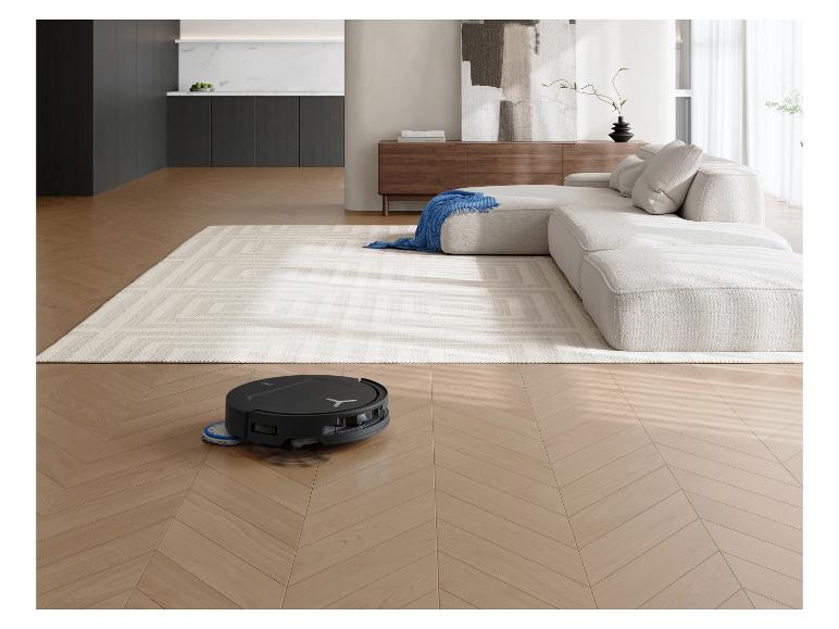 Saugroboter reinigt Holzboden in einem modernen Wohnzimmer mit Sofa und Teppich.