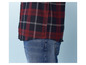 Ein rot-schwarzes kariertes Hemd mit langen Ärmeln, getragen über einer blauen Jeans.