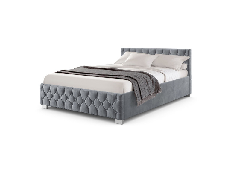 Ein graues Samtbett mit gestepptem Muster und silbernen Beinen.