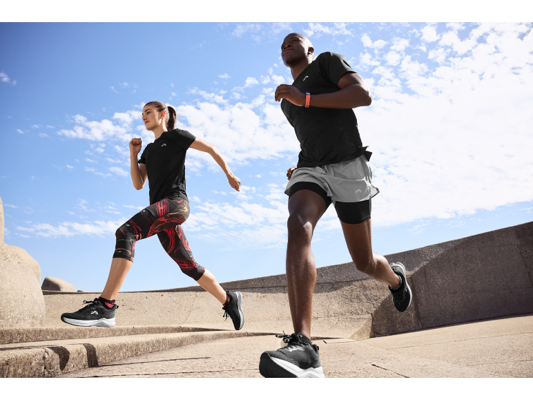 Zwei Personen joggen draußen in Sportkleidung und Laufschuhen.