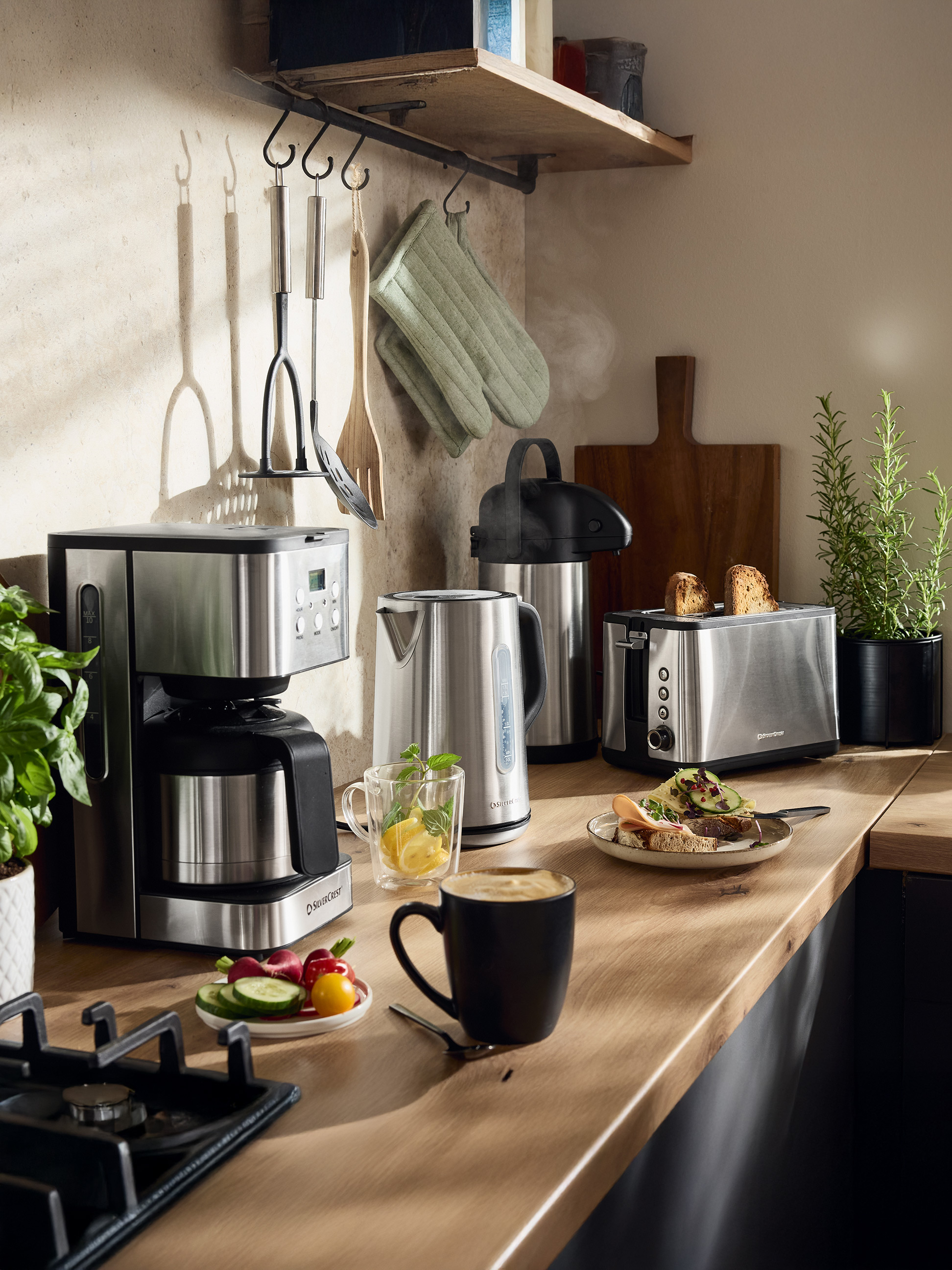 SilverCrest Kaffeemaschine, Wasserkocher und Toaster in einer Küche mit Speisen und Getränken.