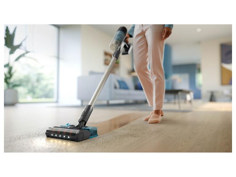 Kabelloser Stielstaubsauger mit LED-Lichtern reinigt einen Holzboden in einem modernen Zuhause.