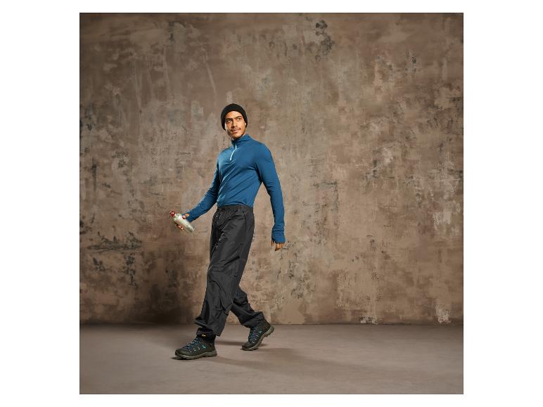 Mann mit blauem Pullover, schwarzen Hosen und Wanderschuhen