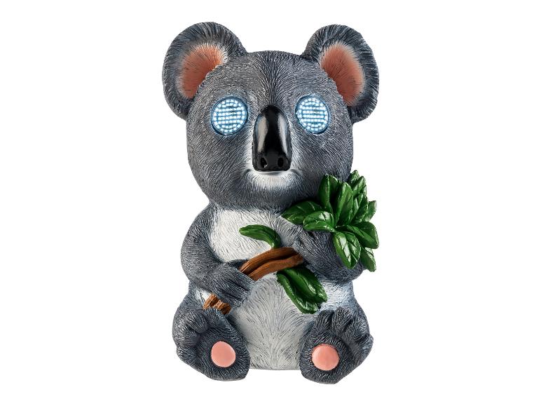 Koala-Figur mit leuchtenden Augen und Eukalyptuszweig.