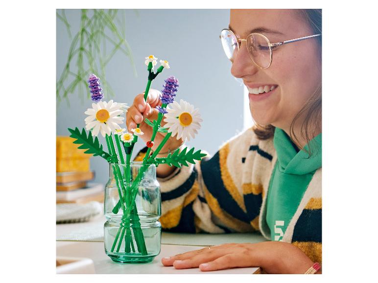Eine Frau arrangiert ein Bouquet aus LEGO BOTANICALS Gänseblümchen in einer Vase.