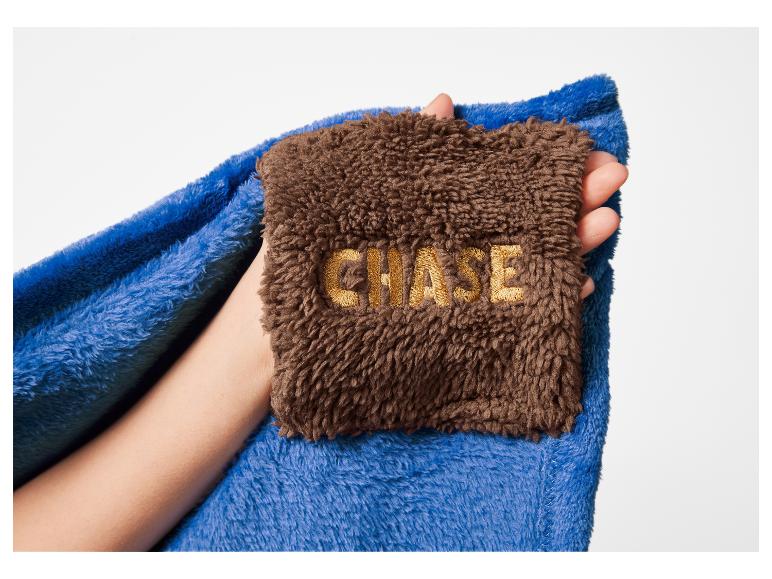 Blaue und braune Decke mit gesticktem „CHASE“-Schriftzug in einer Hand
