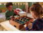 Zwei Kinder spielen mit einem Tischkicker aus Holz in einem gemütlichen Zimmer
