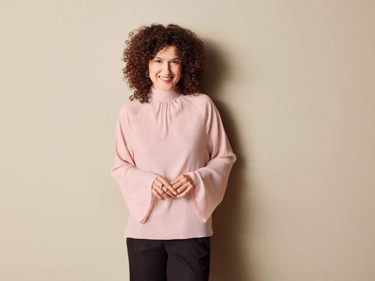 Eine Frau trägt eine rosa Bluse mit Puffärmeln.