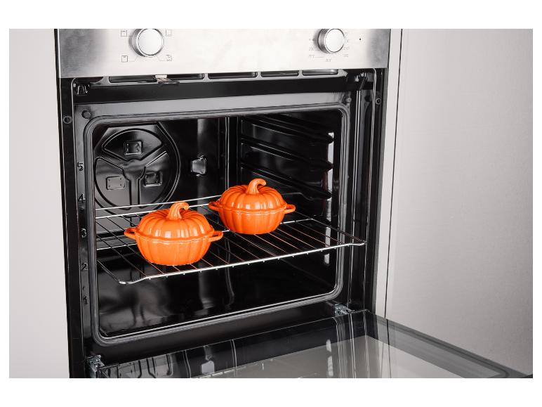 Backofen mit zwei orangefarbenen kürbisförmigen Auflaufformen auf einem Rost.